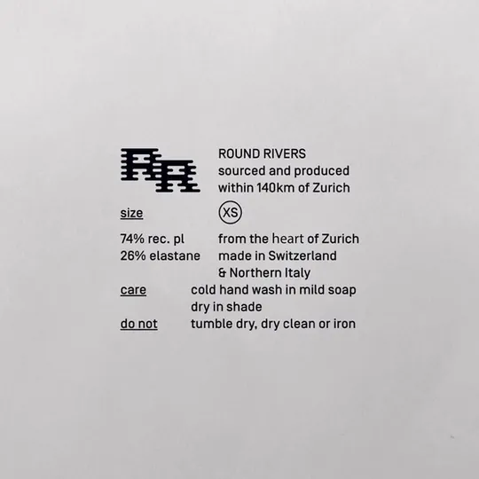 Garment care label as brand voice, tight grotesque left-aligned in labelled rows with a woven glyph mark, Swiss minimal.